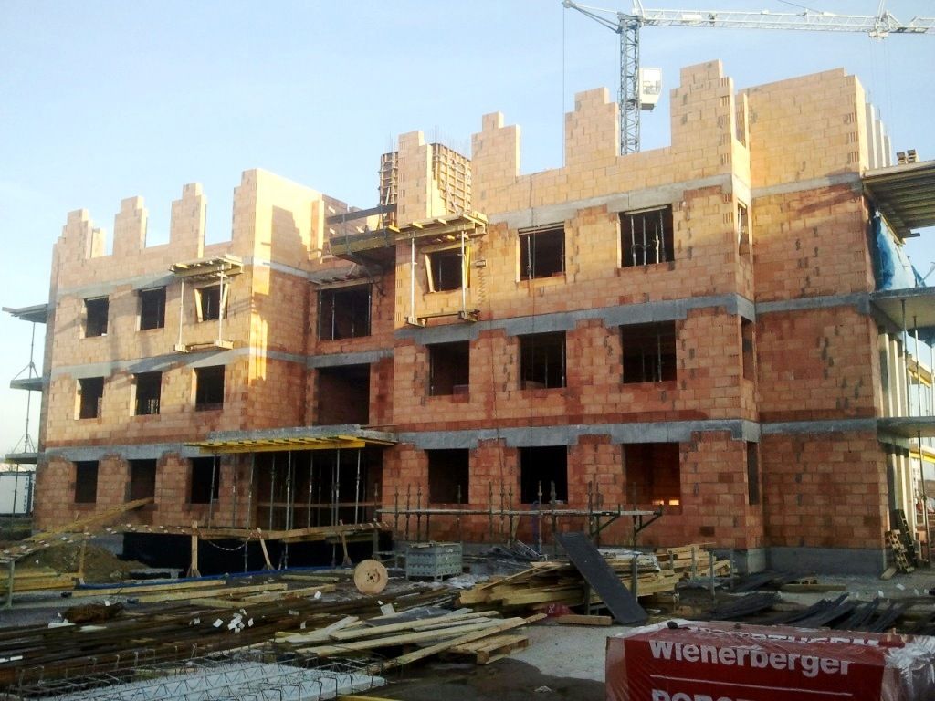 Budynek z cegły przypominający zamek, w trakcie budowy.