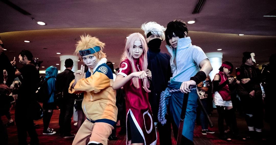 Imagen referencial: Un animado grupo de cosplayers en disfraces de anime posando en un evento de convención en interiores.