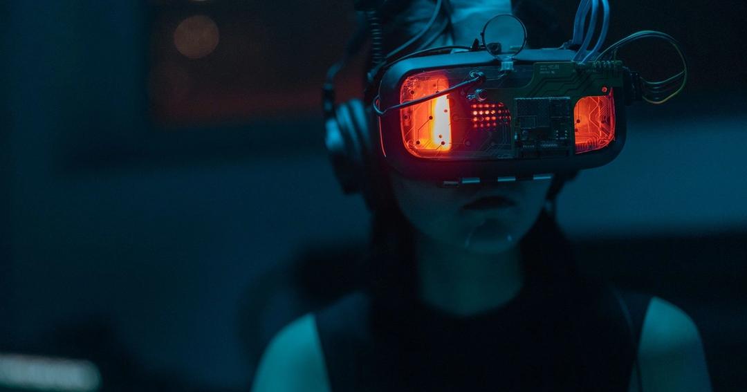 Imagen referencial: Una mujer sumergida en una experiencia de realidad virtual con un visor de VR de alta tecnología en una habitación poco iluminada.