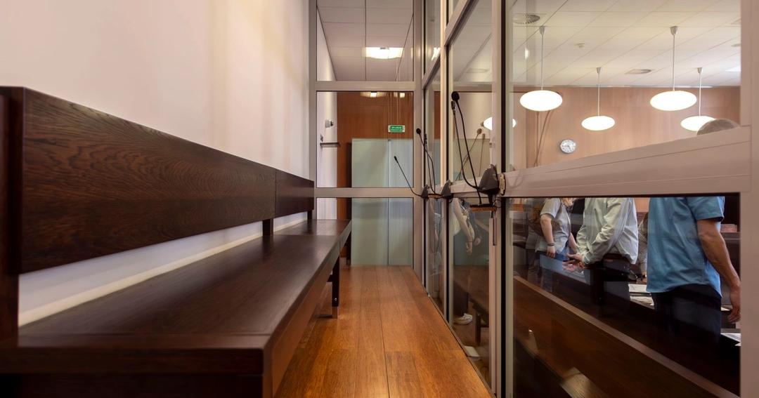 Imagen referencial: Vista interior de una sala de audiencias en Breslavia, Polonia, con bancos de madera y mamparas de cristal.