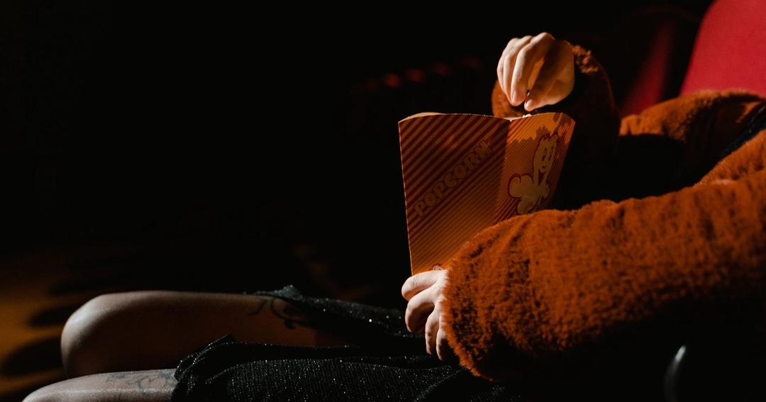 Imagen referencial: Una persona disfrutando de palomitas durante una película en un cine interno, sentada cómodamente.