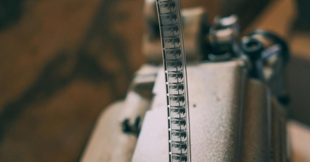 Imagen referencial: Primer plano de una cinta de película vintage en un proyector, mostrando cine clásico.