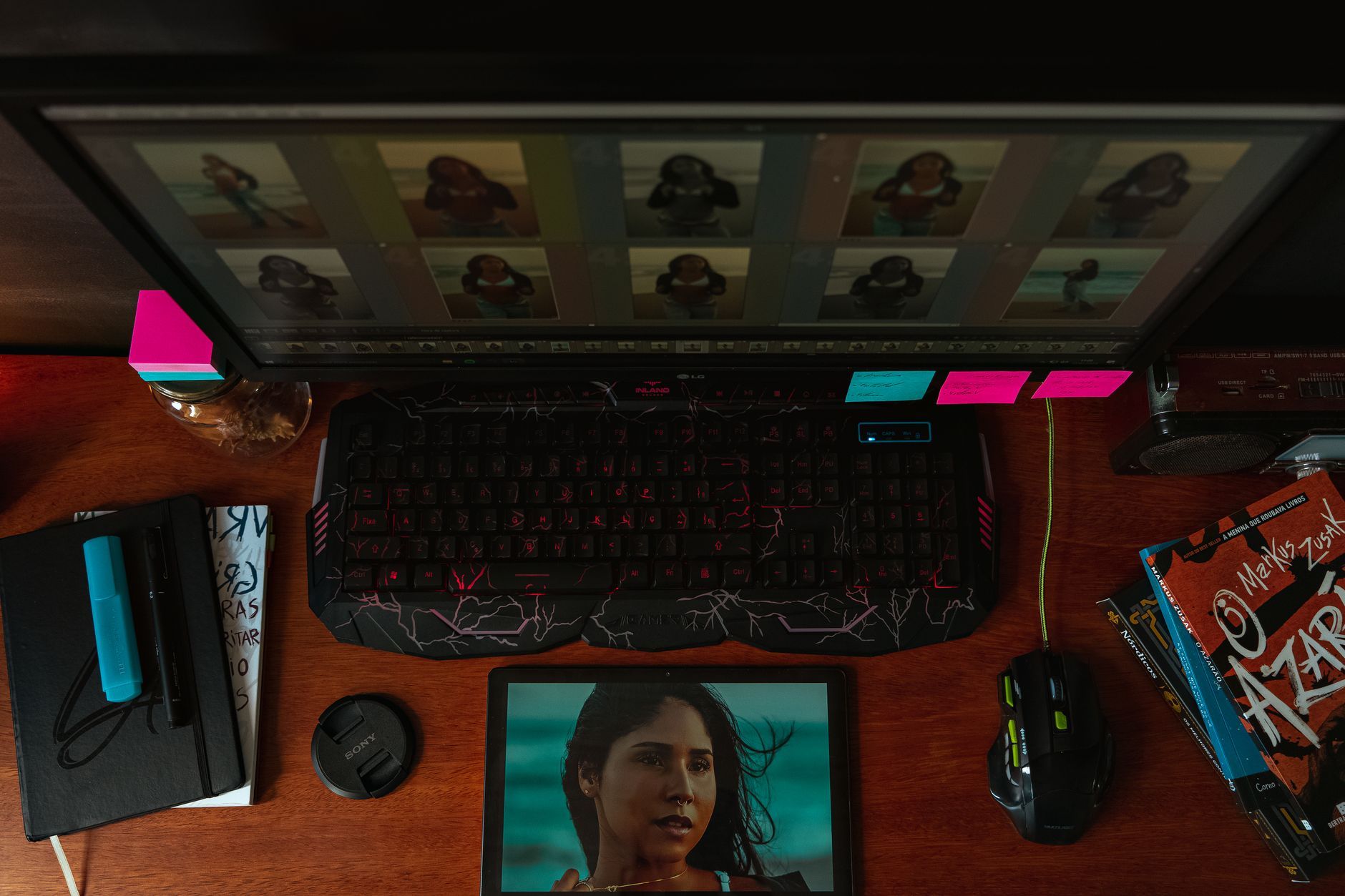 Imagen referencial: Vista superior de un espacio de trabajo creativo con un monitor, teclado y herramientas de edición de fotos sobre un escritorio de madera.