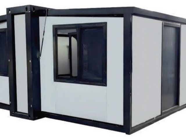 Das Faltcontainerhaus aufgeklappt, mit dunklem Rahmen, beiden Seitenflügeln und Fenstern.