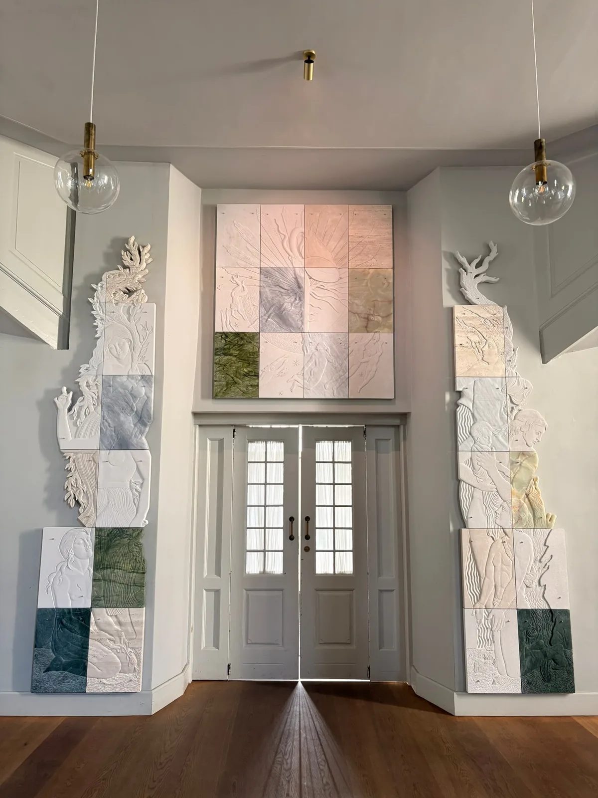 Pale sculptural relief panels with figures and plant forms surrounding a church doorway.