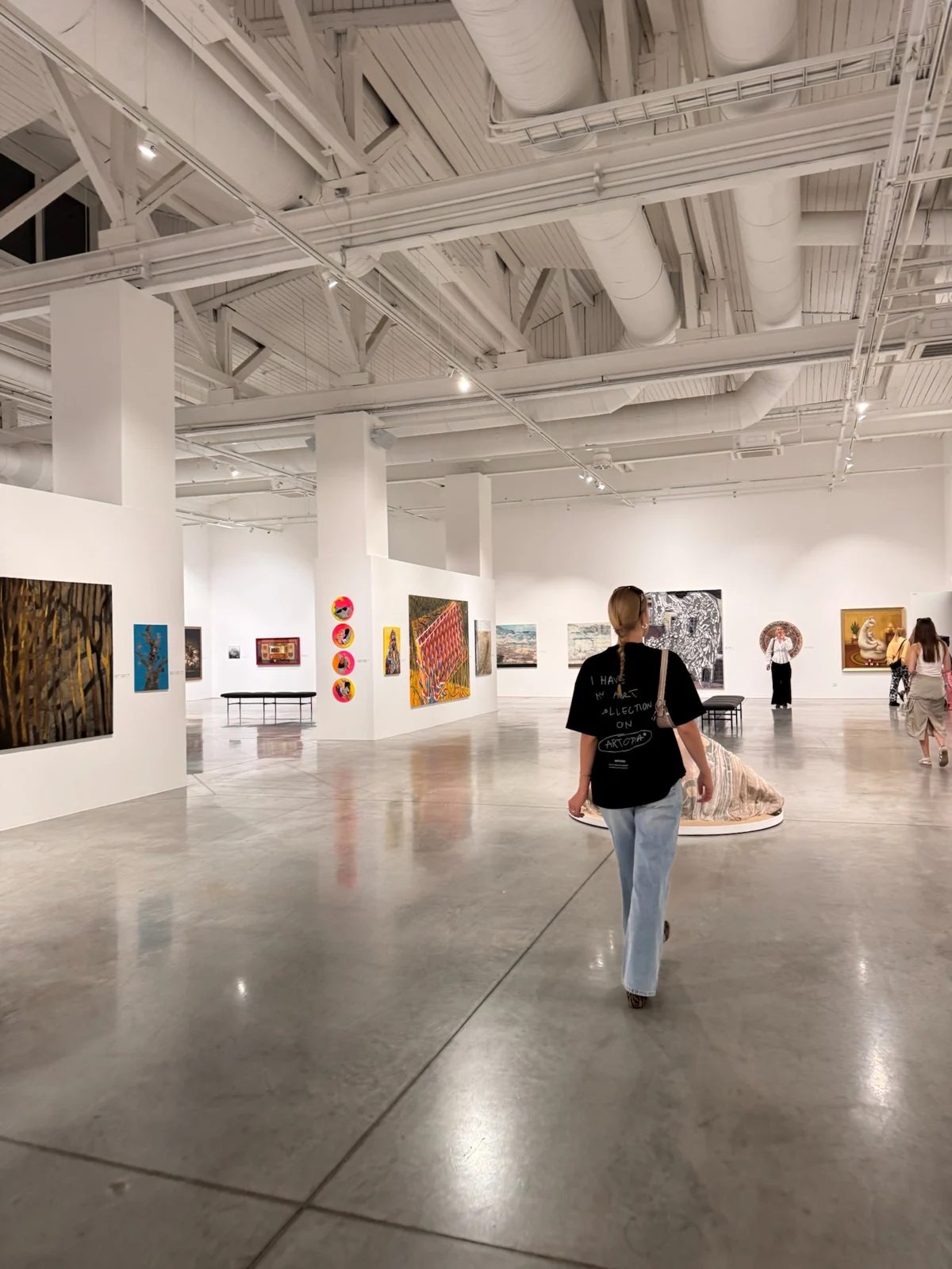 Visitors viewing artworks in Zuzeum museum’s spacious gallery beneath a high white ceiling.