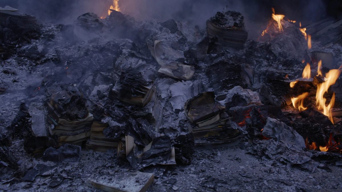 A still from Hikaru Fujii’s Trinity, 2026, showing burning stacks of paper and ash.