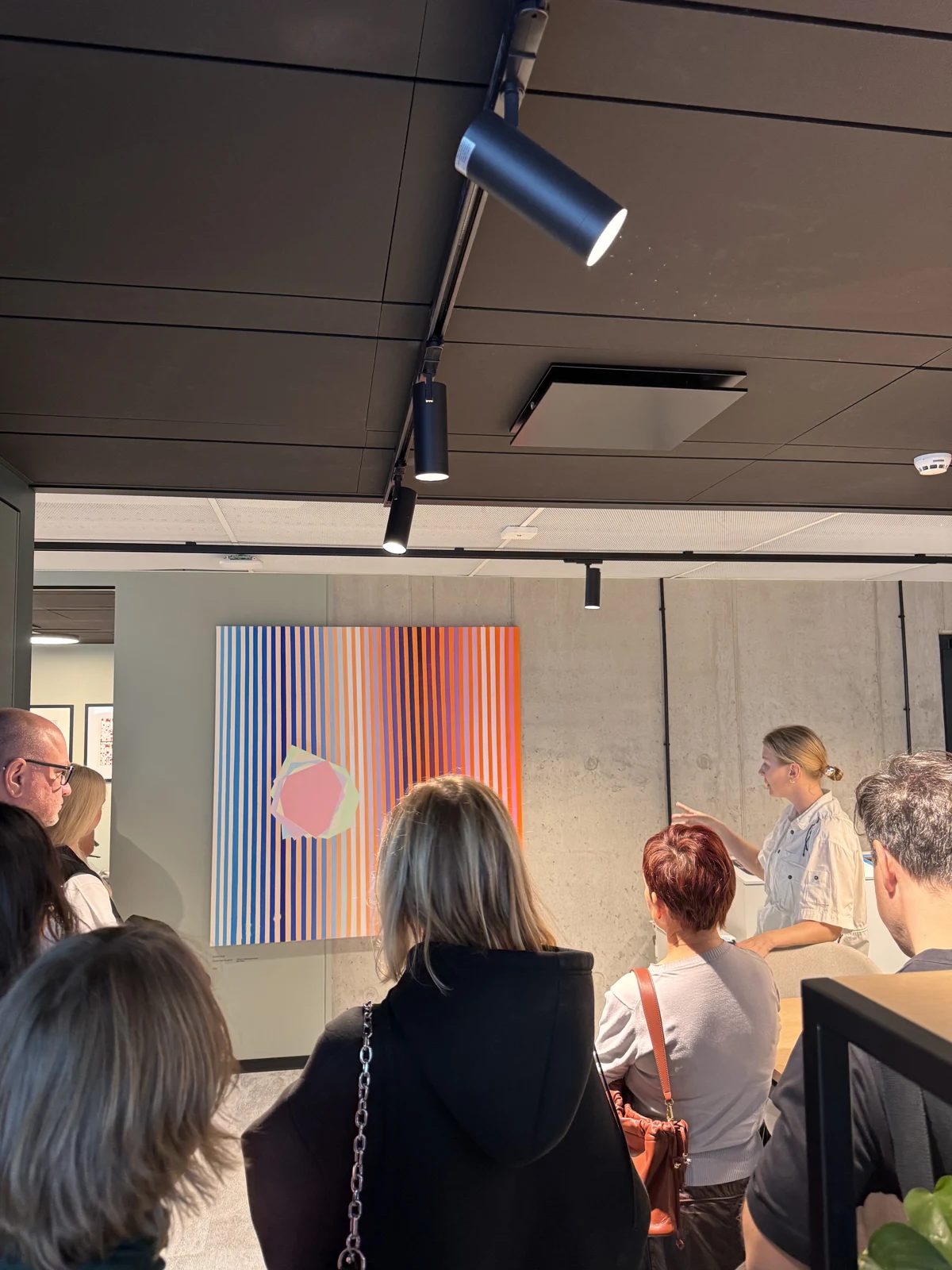 Visitors listening to a guide beside a colourful striped painting at Sunly.