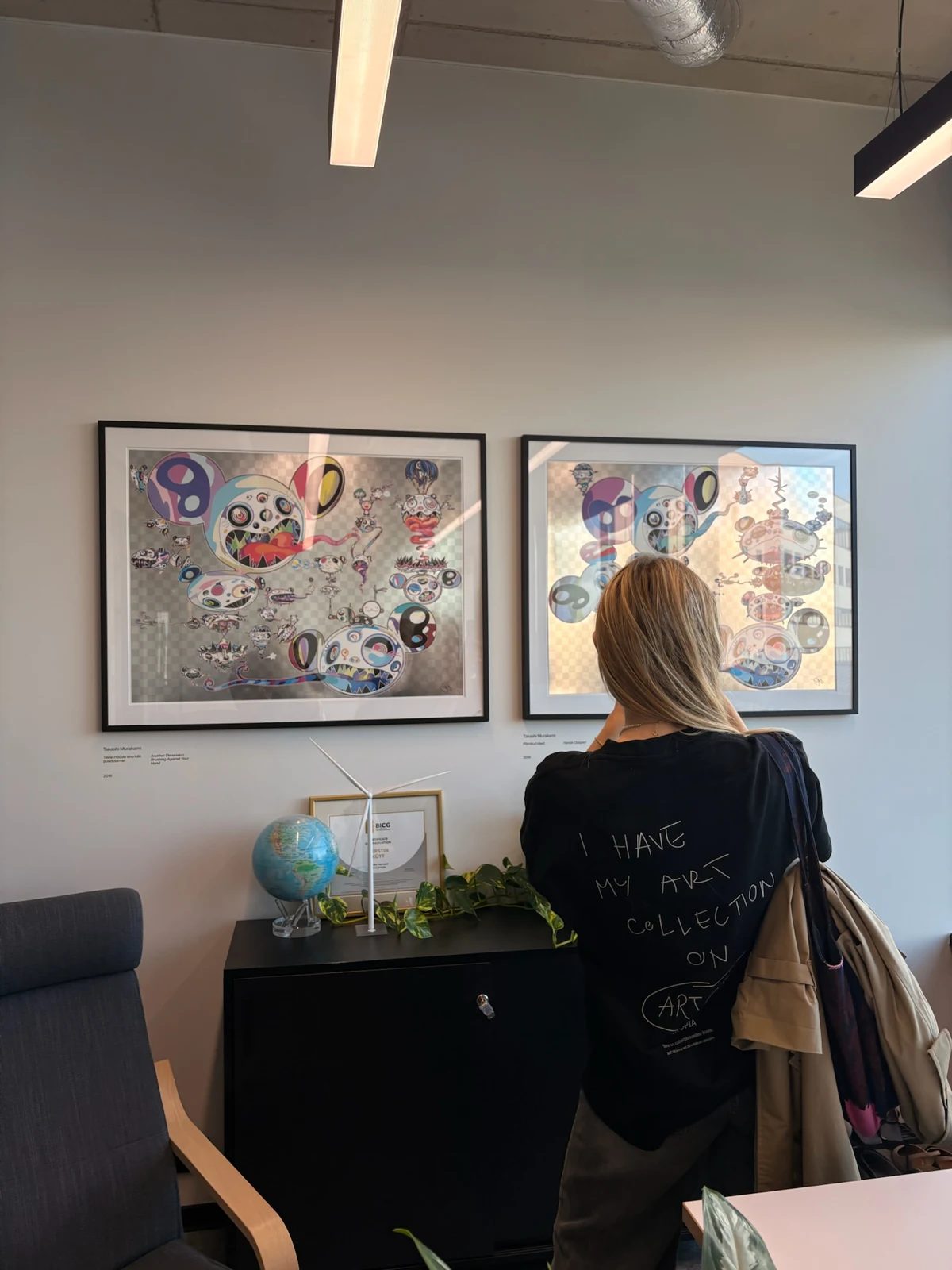 A visitor viewing two framed colourful prints in an office at Sunly.