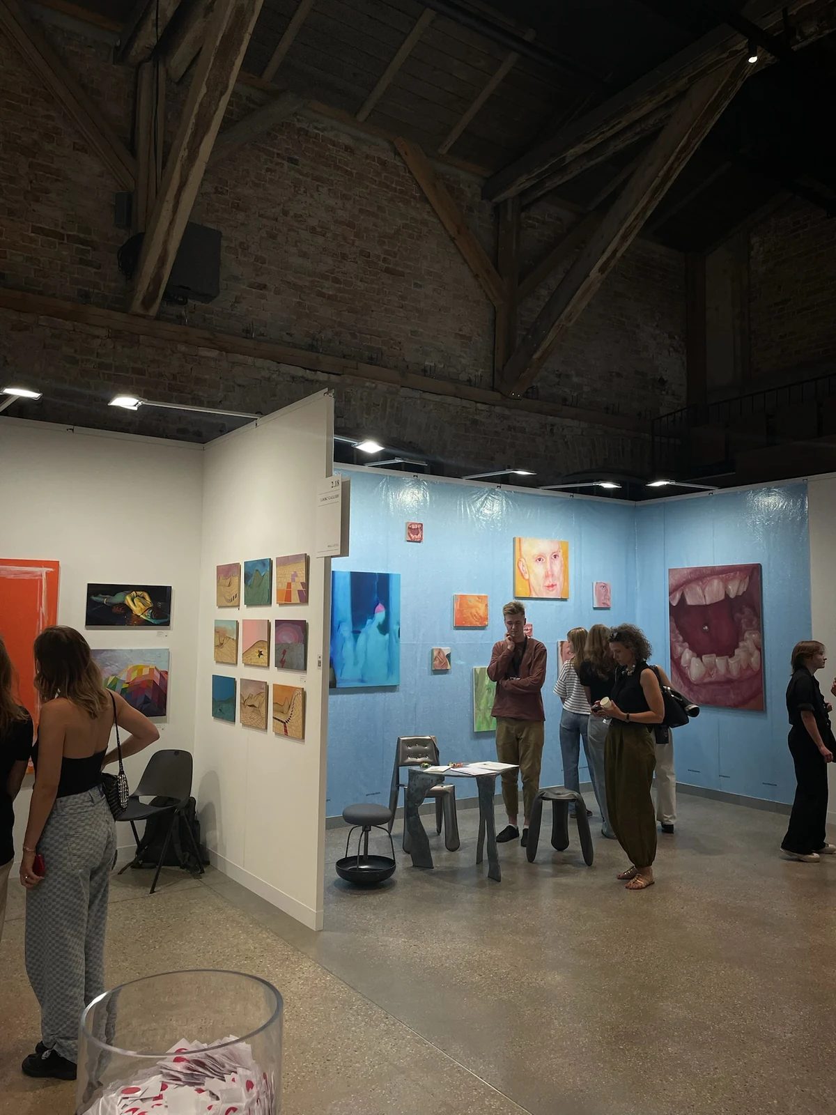 Visitors exploring colourful paintings at Riga Contemporary beneath Hanzas Perons’ timber beams.