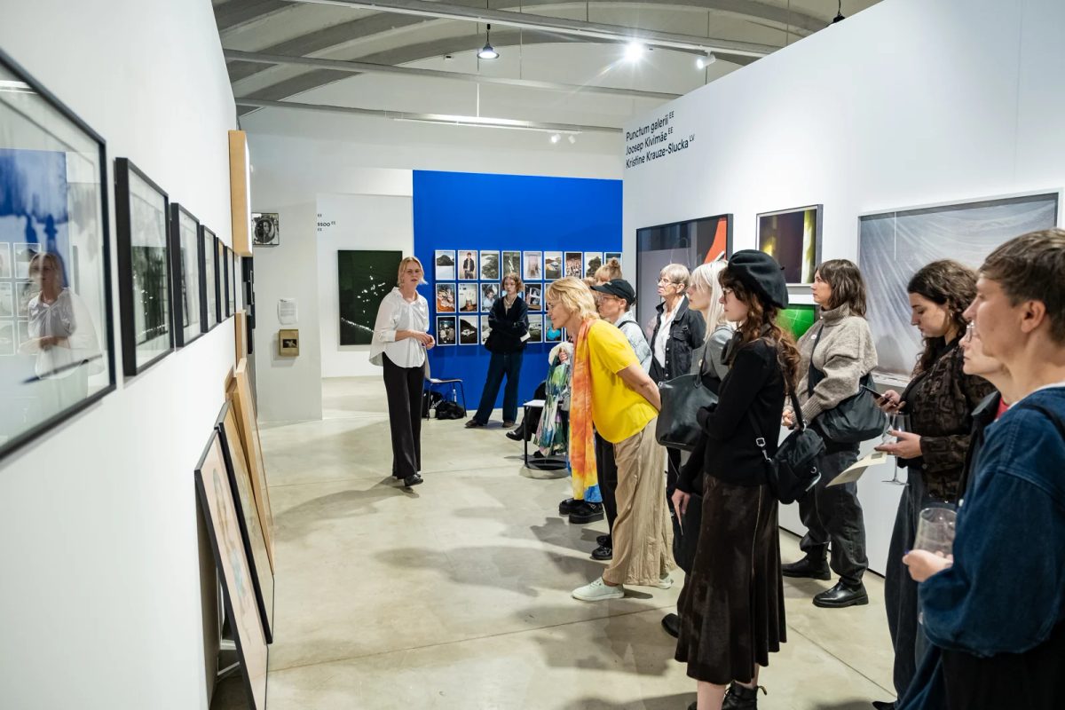 Visitors listening to a guide while viewing framed photographic works at FOTO Tallinn.