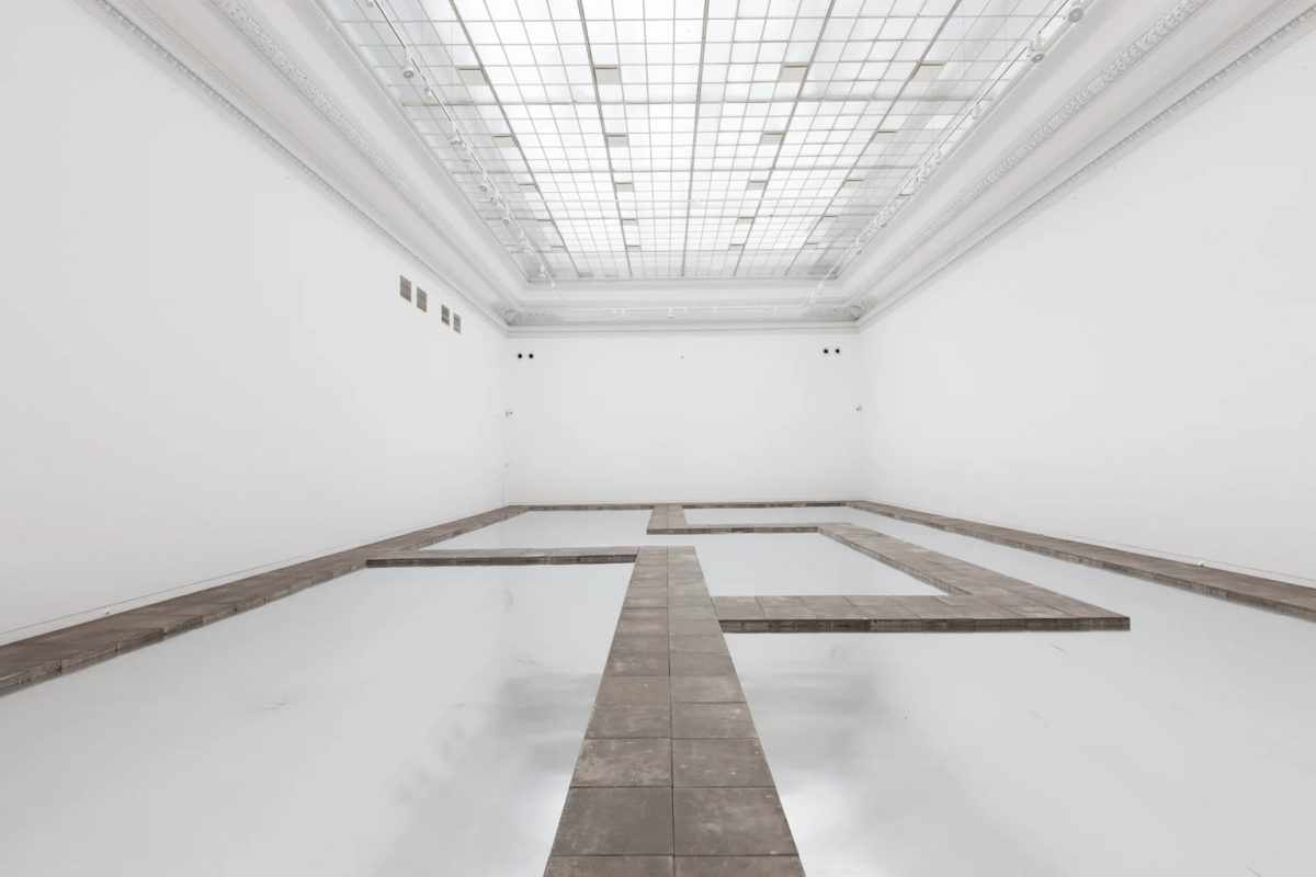 Koji Kamoji’s installation Silence and the Will to Live, with paving-slab paths across reflective aluminium sheets in a skylit gallery.