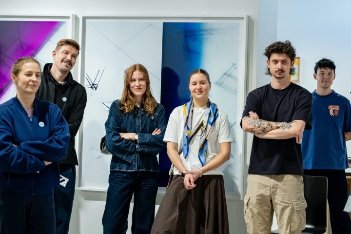 Six people standing in front of framed photographic artworks at FOTO Tallinn.