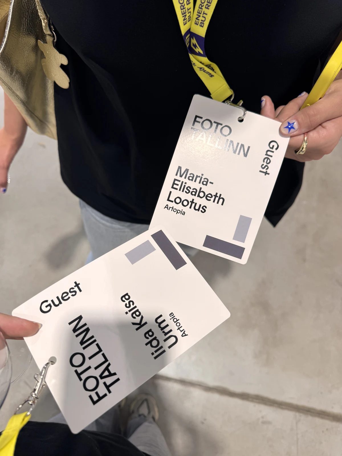 Two FOTO Tallinn guest badges held by visitors.