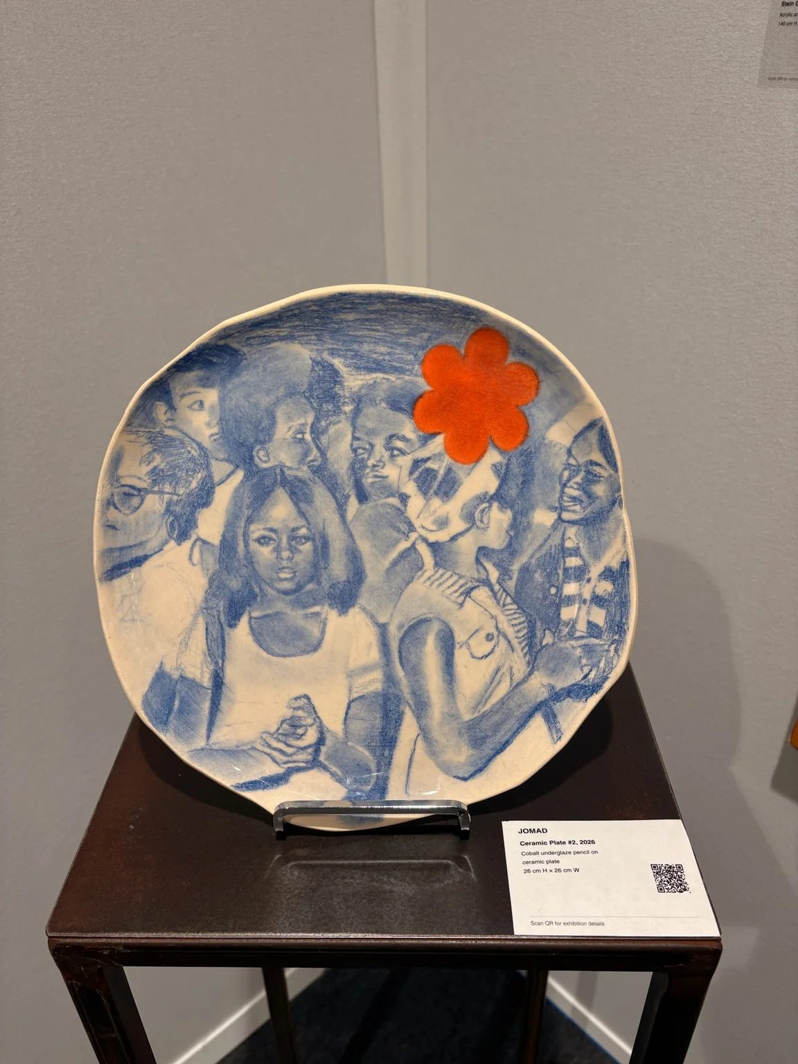 Jomad’s Ceramic Plate #2 (2026), with blue group portraits and an orange flower, shown by OOA Gallery at AKAA.