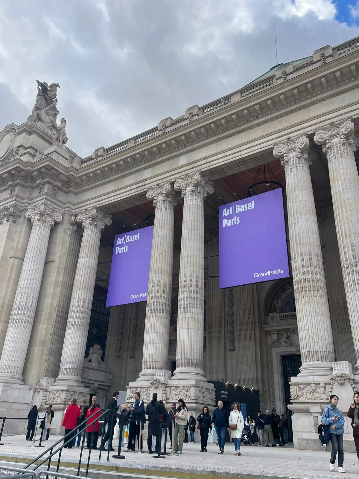 Visitors outside the Grand Palais in Paris beneath purple Art Basel Paris banners.