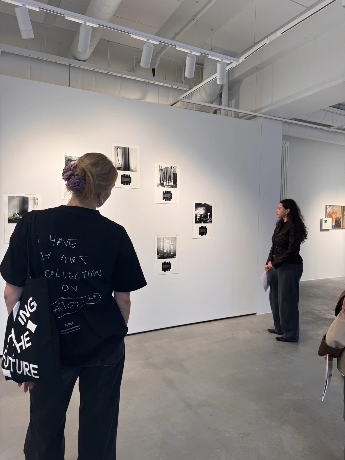 Visitors viewing photographic works displayed on a white gallery wall.