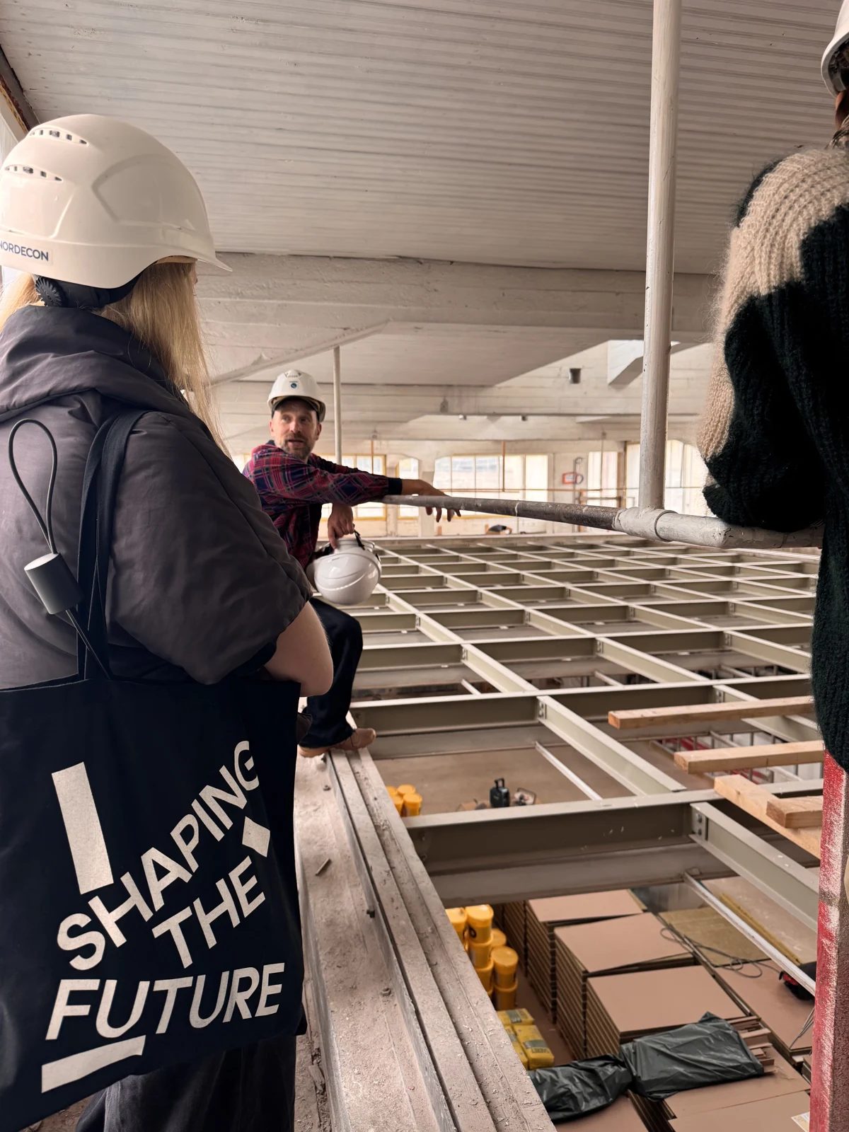 Visitors wearing hard hats tour an unfinished interior at Tallinn Art Hall.