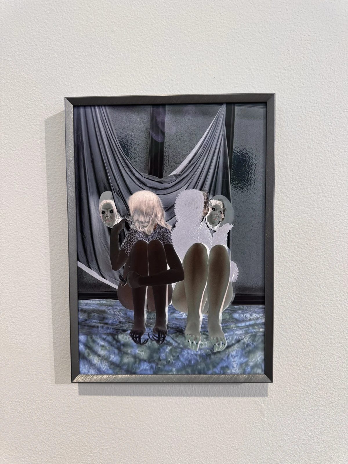 A framed photographic composition showing three figures against draped fabric.
