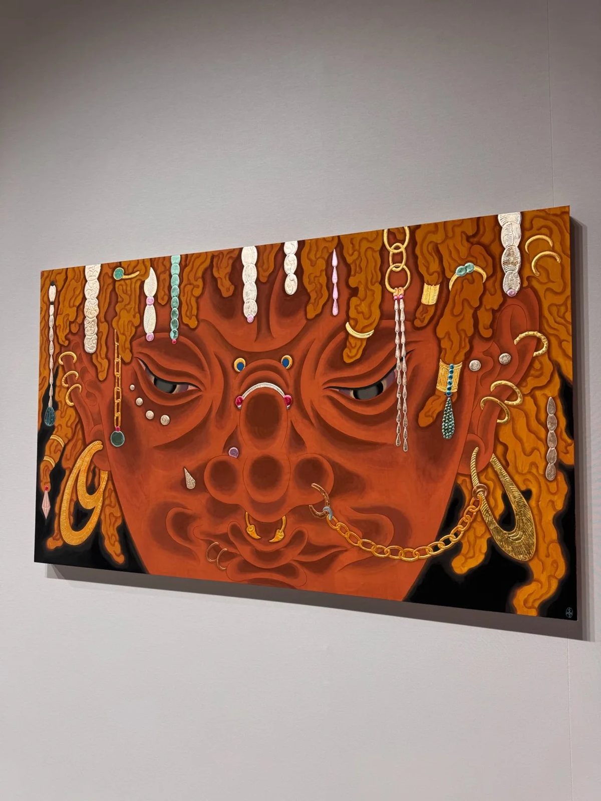 Tseng Chien-Ying’s Vesper (2026), an orange-red face adorned with chains, earrings and piercings, at Asia NOW.