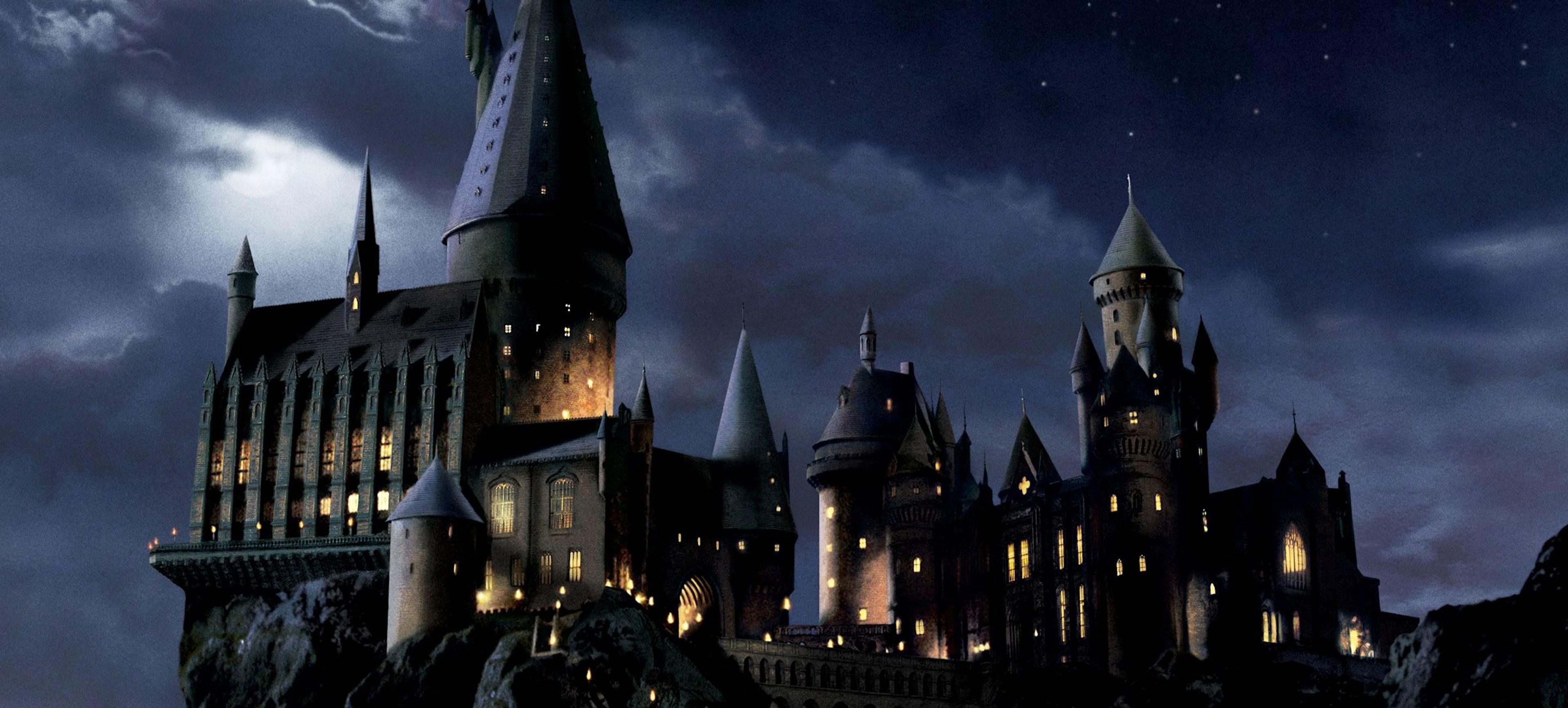 Hogwarts castle is lit against a dark night sky.