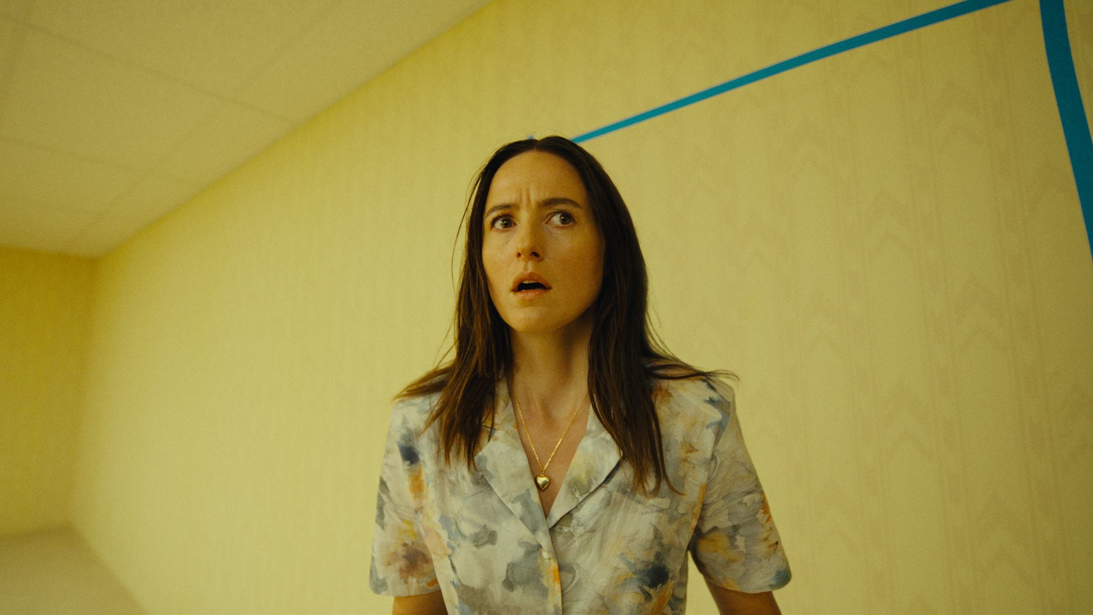 Renate Reinsve stands inside a yellow liminal room in official A24 Backrooms imagery.