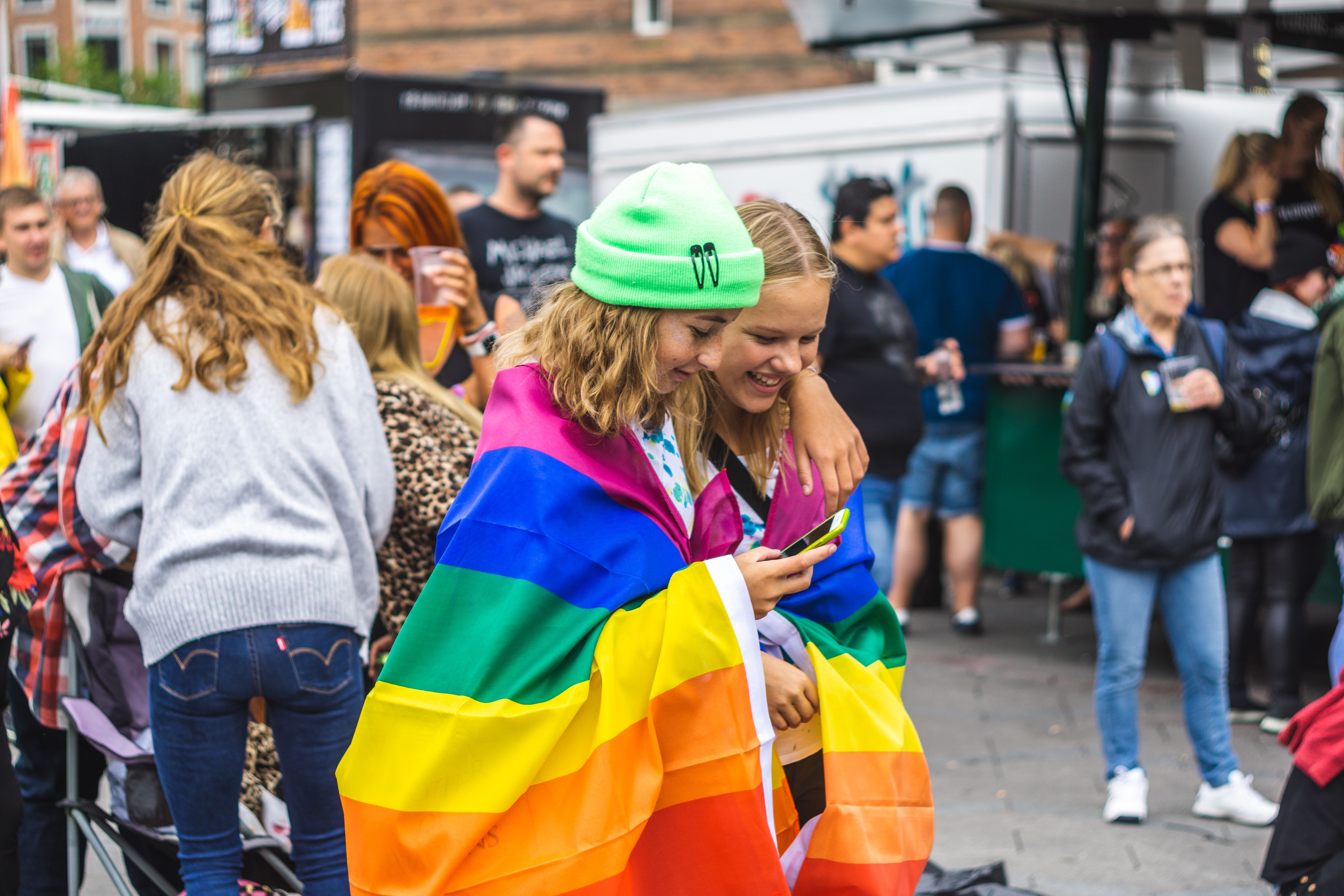 To jenter som har et regnbueflagg surret rundt seg