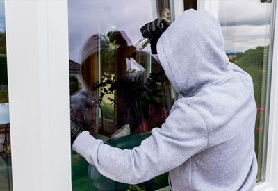 Innbruddstyv som åpner opp vindu for å komme seg inn i bygget