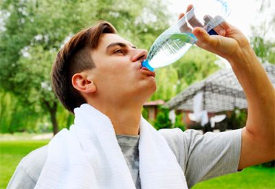 Gutt som drikker av en vannflaske etter trening