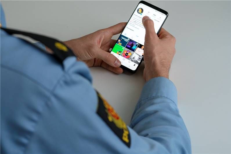 Bilde av en politibetjent som sjekker politiets Instagram-konto