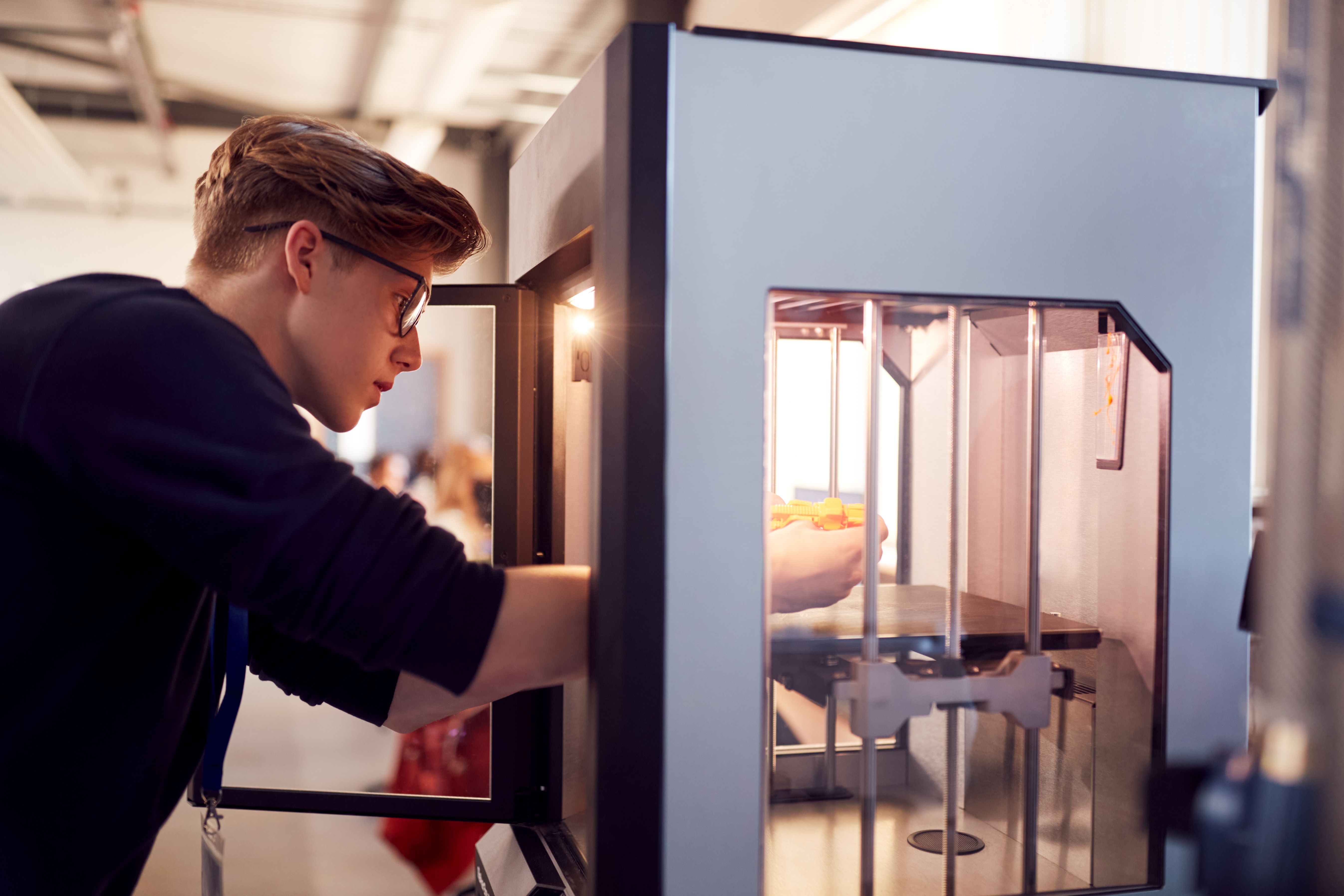Gutt med briller som bruker en 3D-printer.