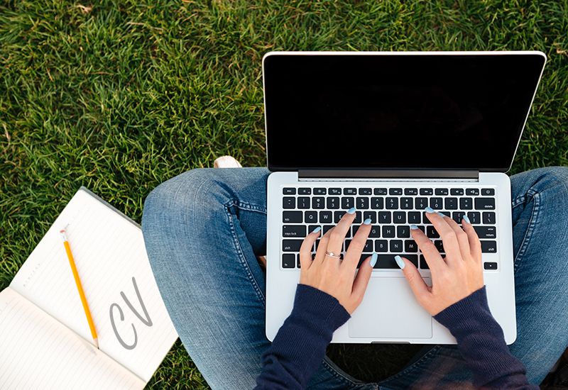 Jente sitter ute og skriver på laptop (colourbox.com)