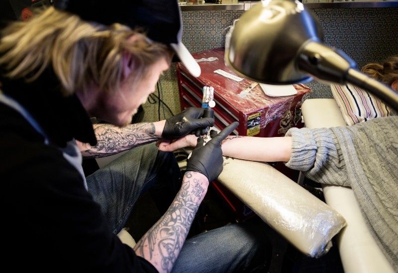 Ung person som får tatovering på armen
