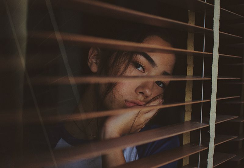 Jente ser ut gjennom vinduet og ser lei seg ut (Foto: Joshua Rawson-Harris på Unsplash.com)
