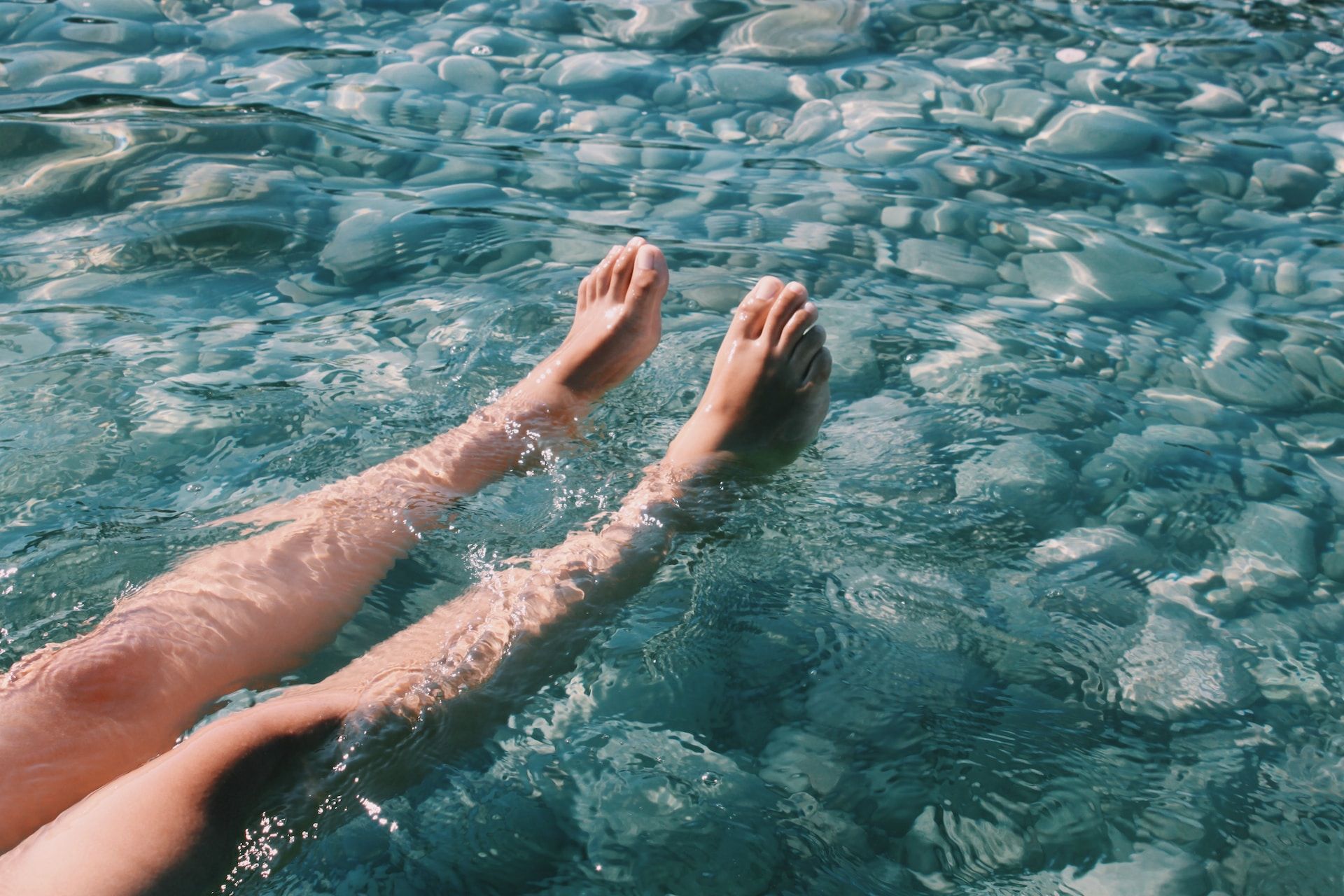 Nærbilde av føttene til en person som flyter i turkist vann