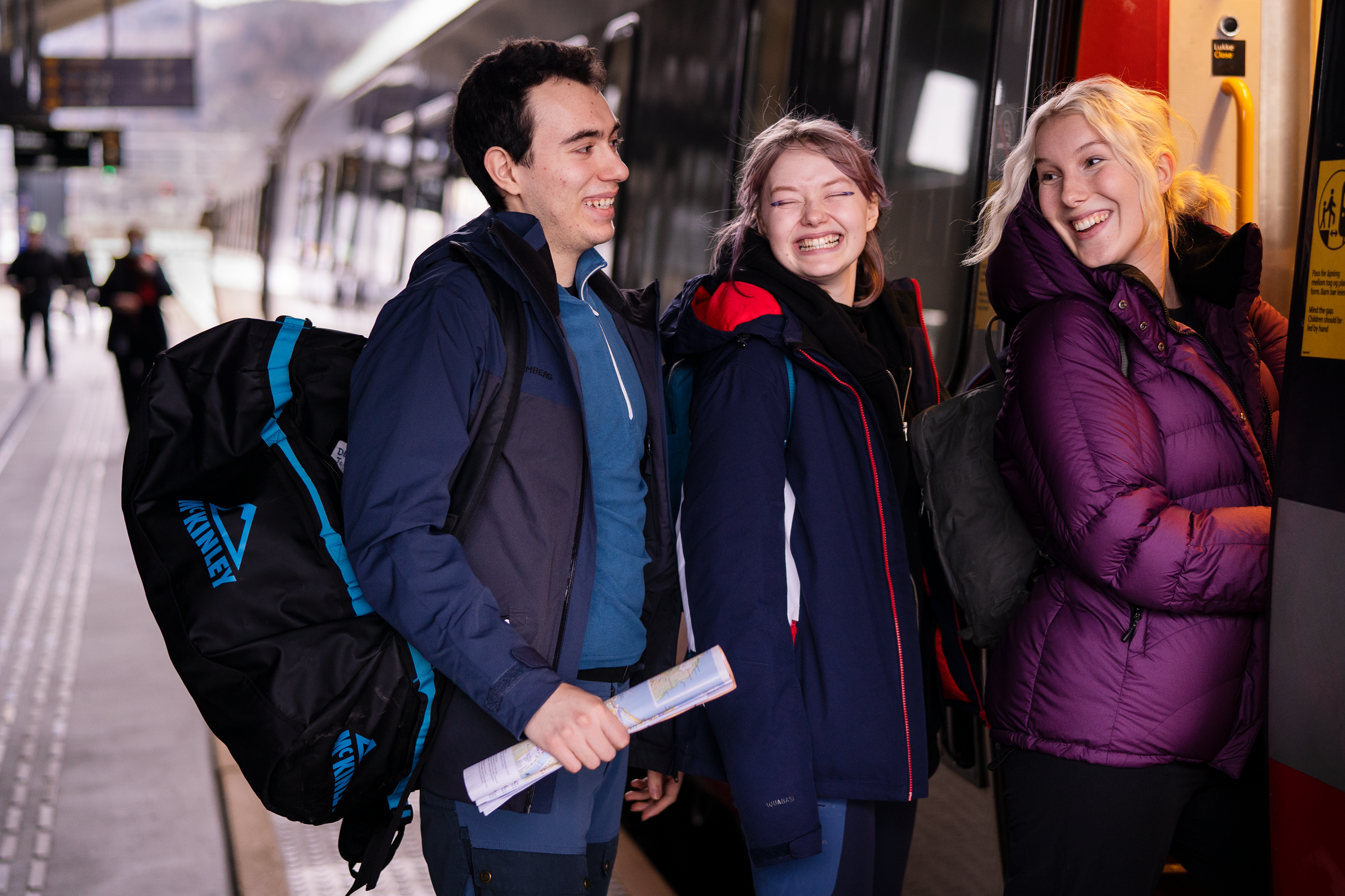 Tre unge personer som er forventningsfulle mens de hopper på et tog