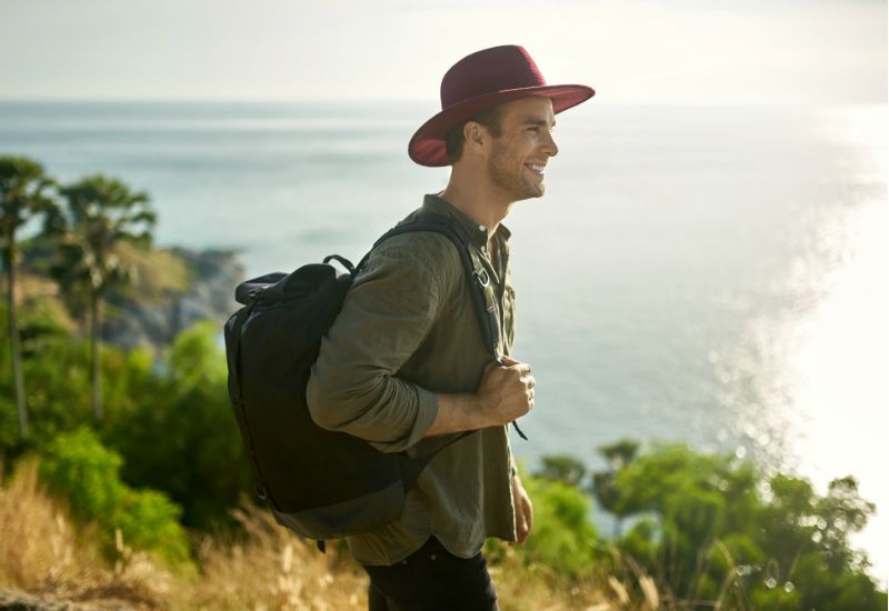 Smilende mann står på klippe med utsikt over havet (foto: colourbox.com) 