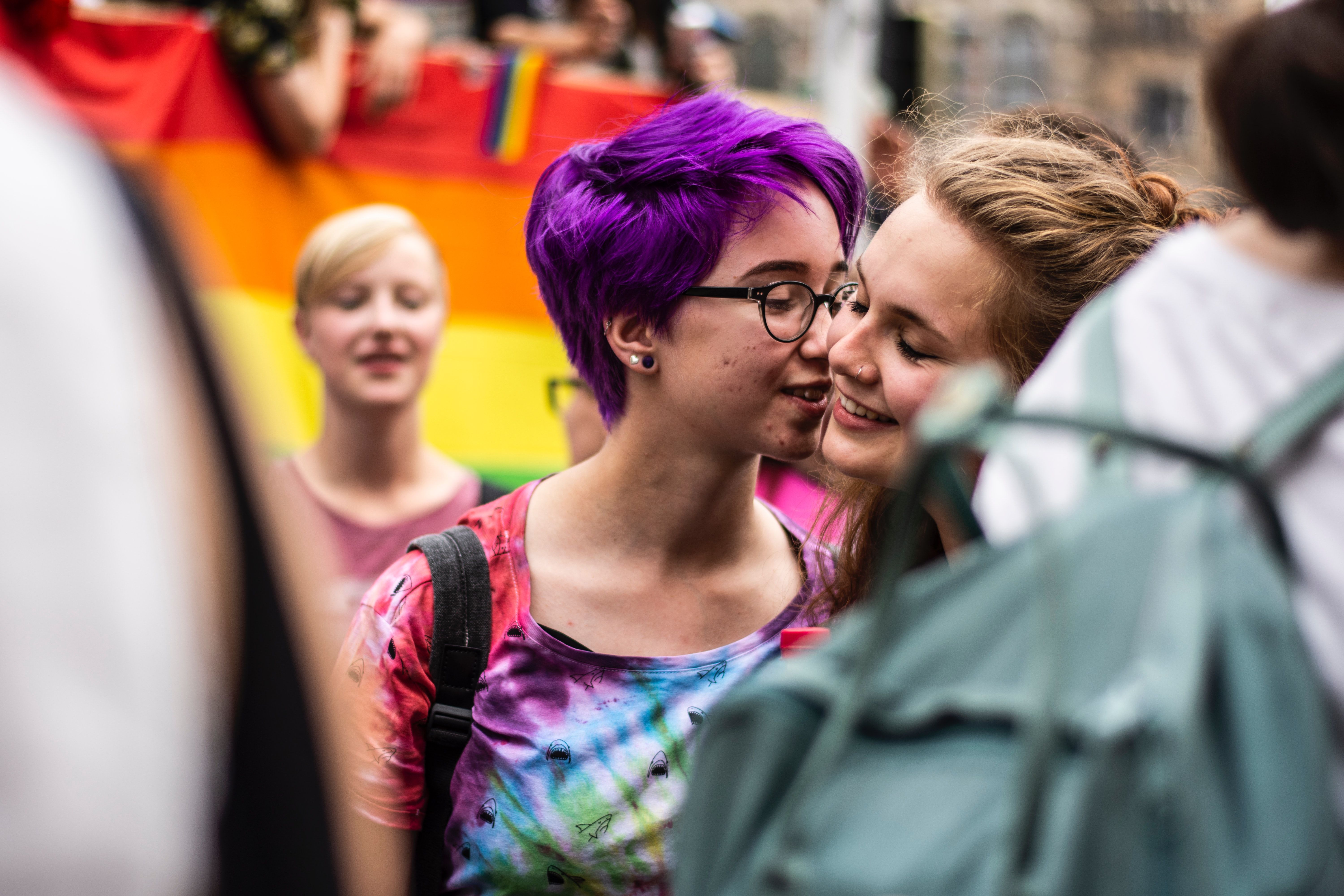 To unge jenter på Pride-feiring som lener seg mot hverandre og ser forelska ut
