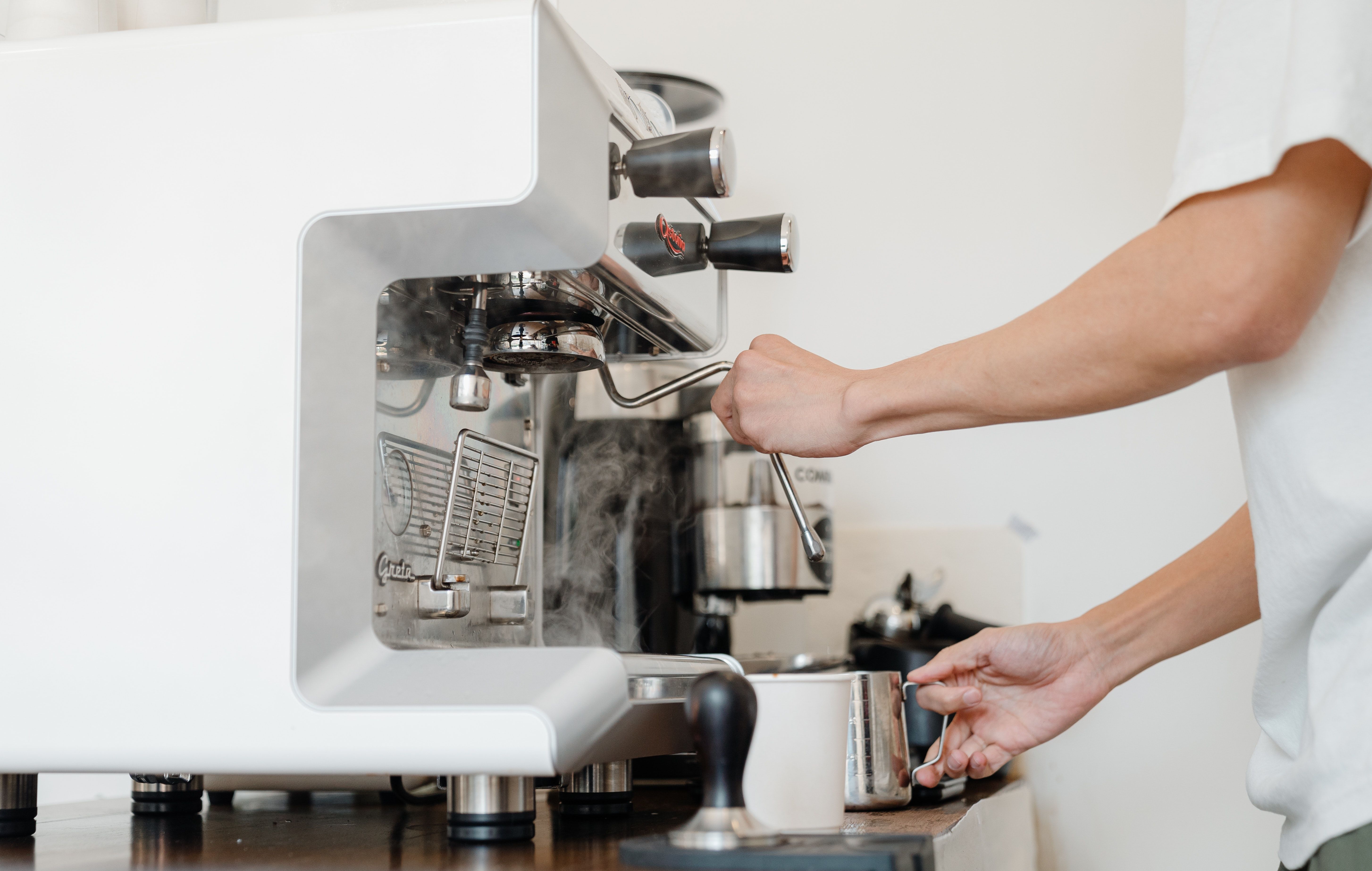 Person lager kaffe med en kaffemaskin