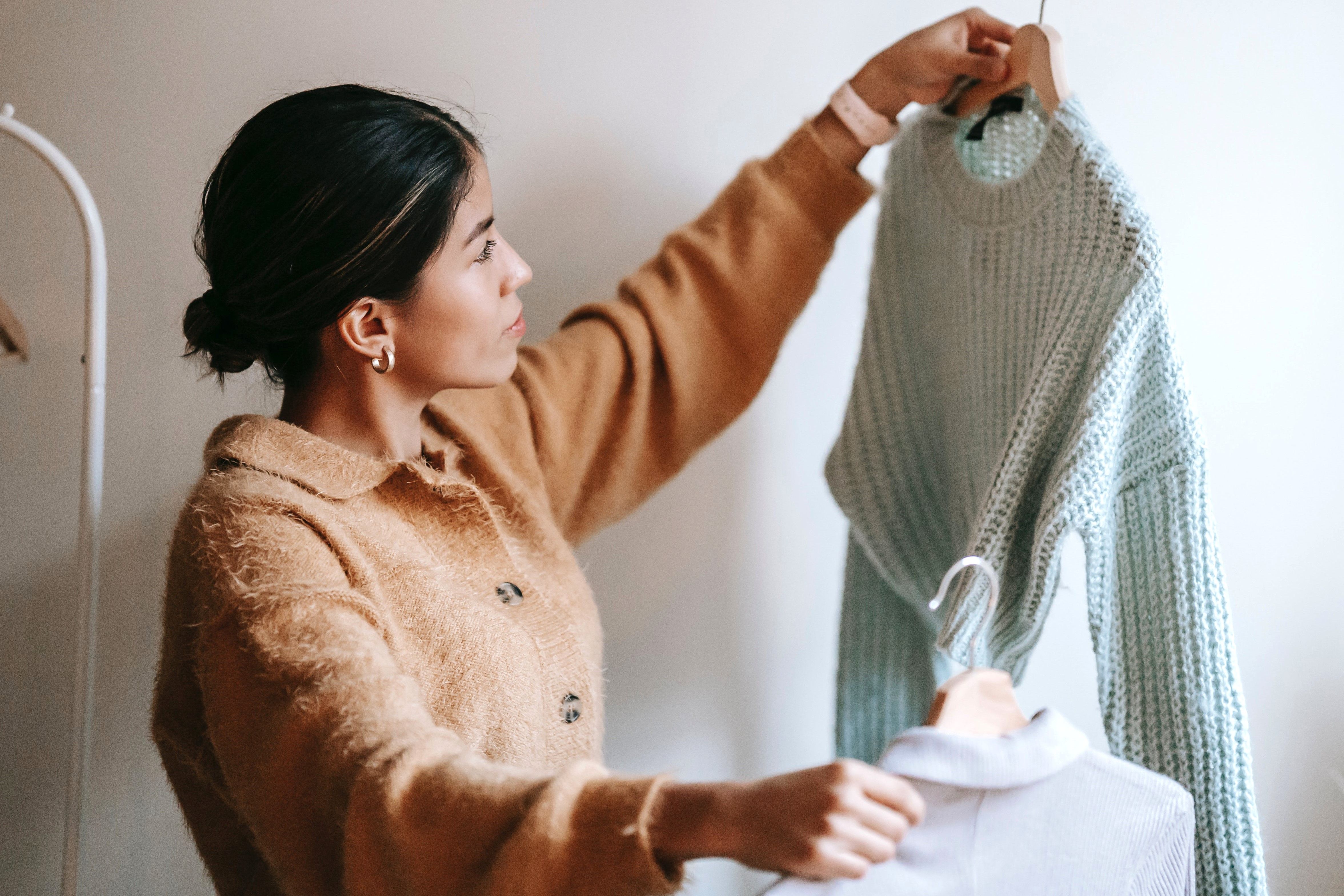 Ung kvinne holder opp og sammenligner to gensere.