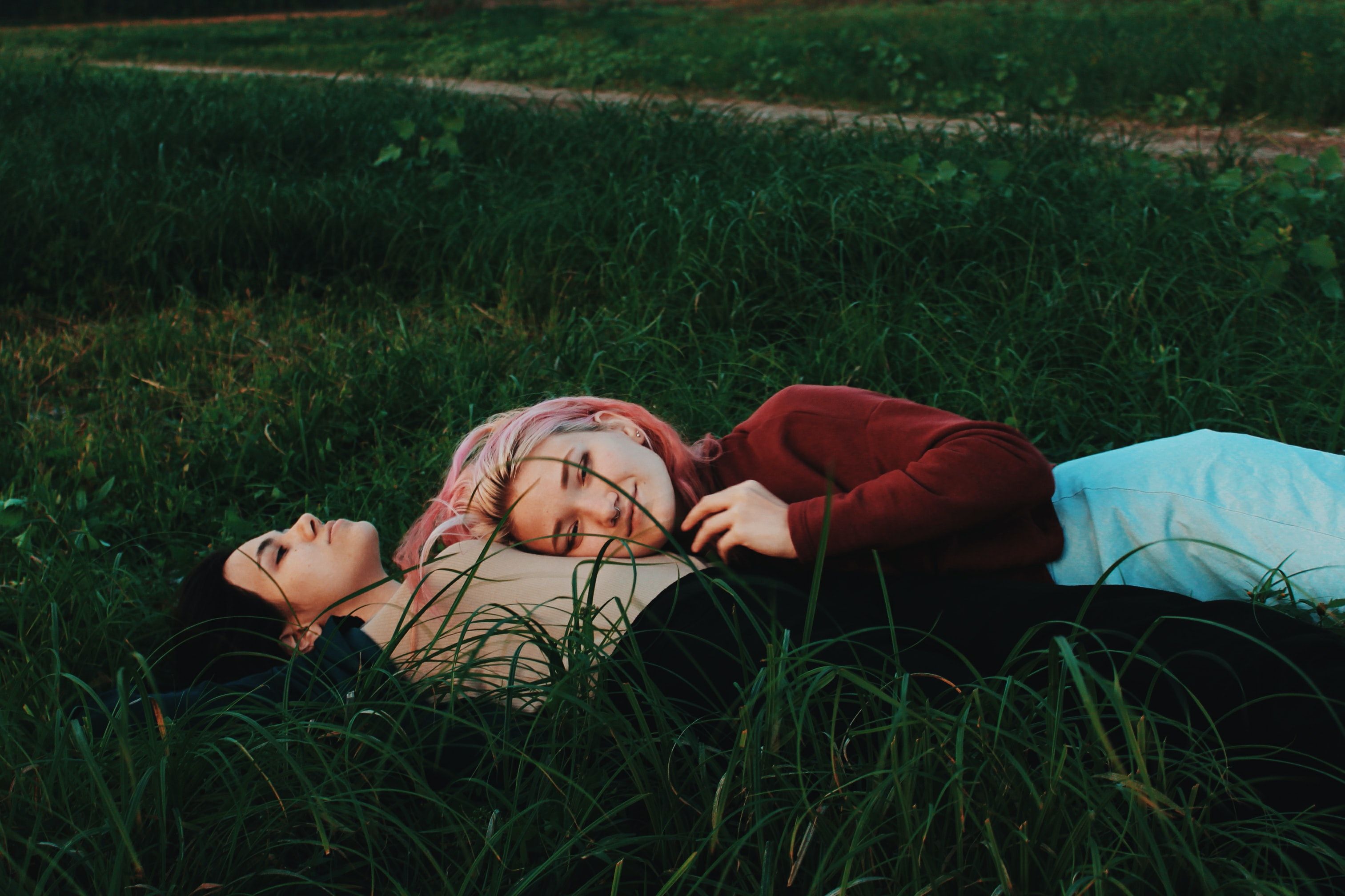 To jenter som ligger i gresset. 