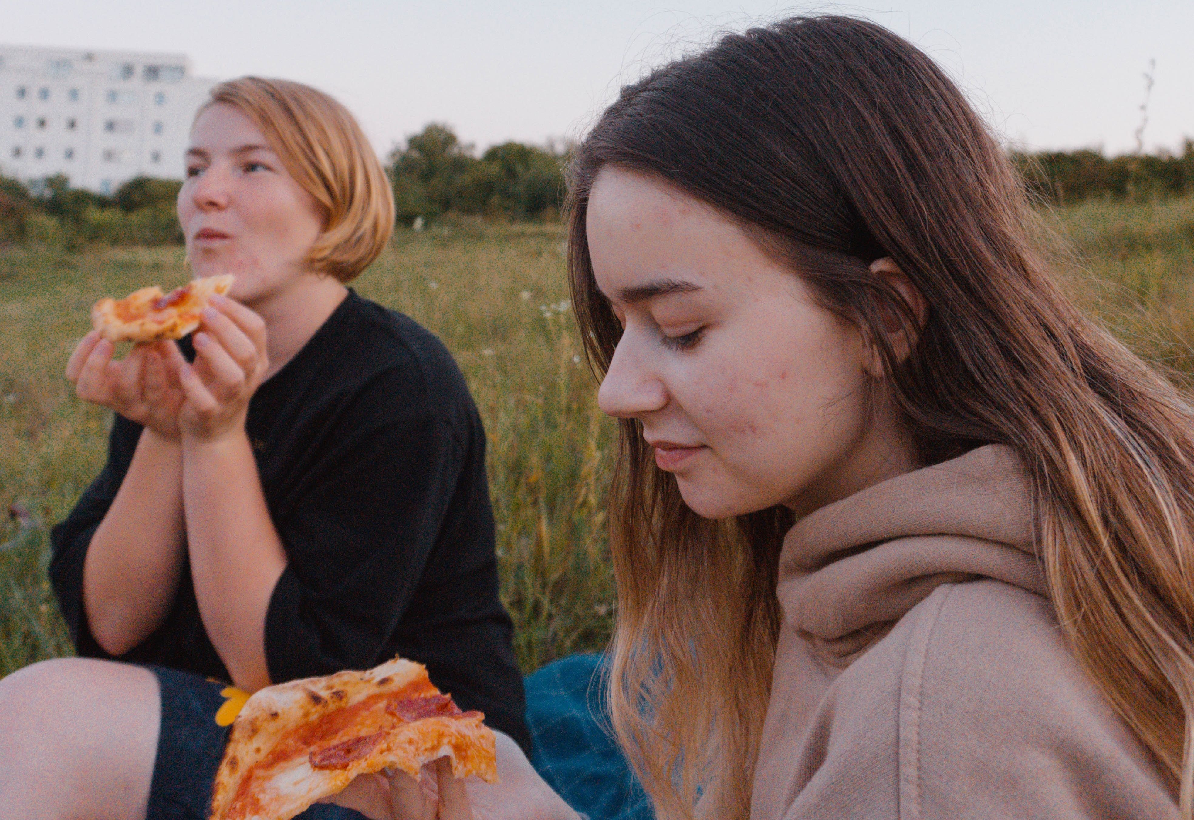 To unge jenter som koser seg med pizza