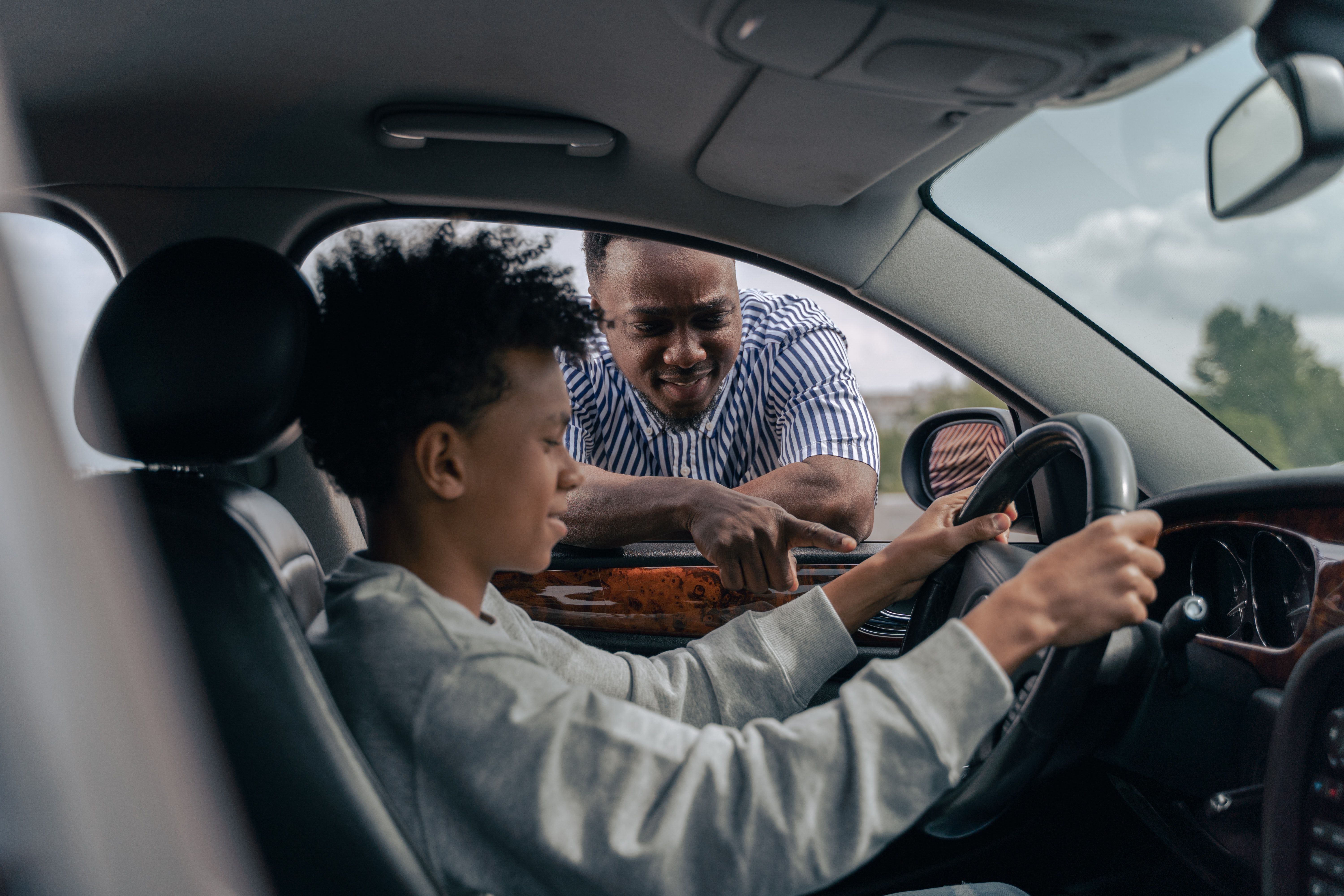 Ung person i førersetet får instruksjoner om bilkjøring av en voksen.