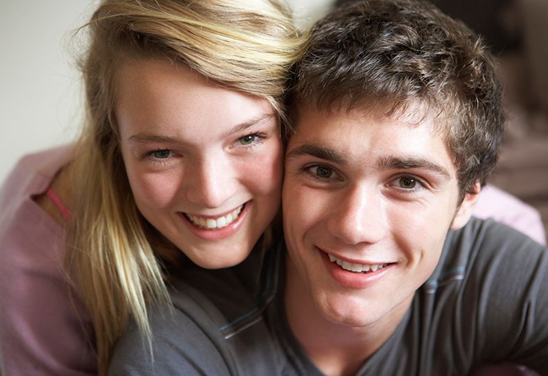 To unge som poserer smilende som et par til kamera.