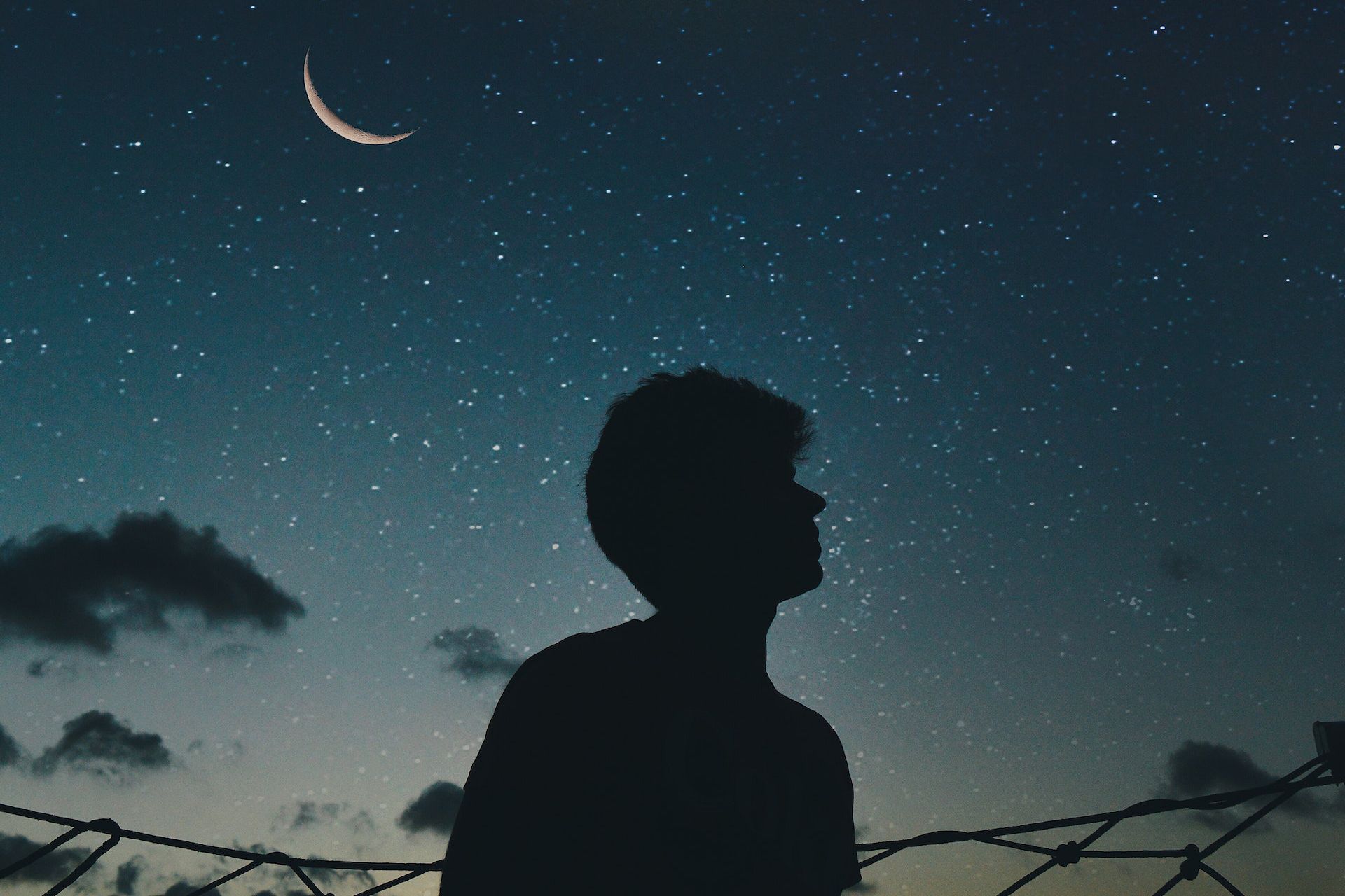 Mørk silhuett av en ung person mot nattehimmelen.