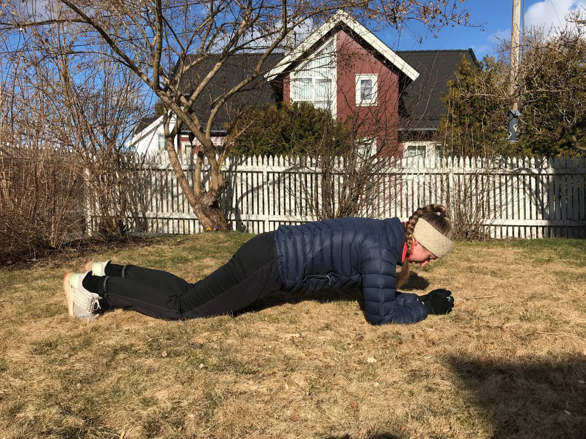 Ung jente gjennomfører planken på knærne hjemme i hagen