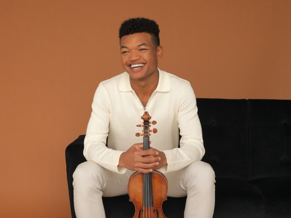 Randall Goosby seated, holding his violin
