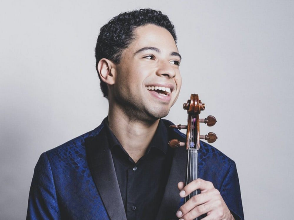 Jordan Bak smiling, holding his viola
