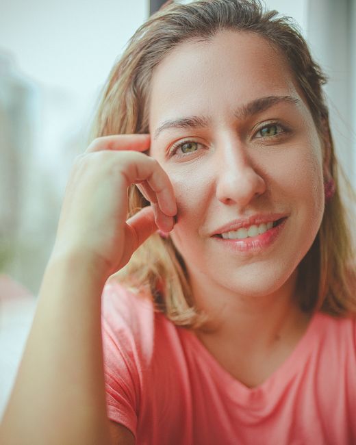 Abelia Torres, reviewer — professional headshot of a smiling woman in a pink shirt by a window.