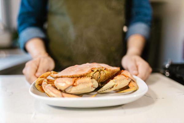 Chef holding a freshly prepared crab plate in a seafood restaurant